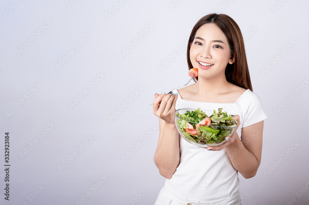 Beautiful young asian eating salad with big smile happy beaming face in seamless white isolated background. Diet healthy concept. Her face and skin are healthy, fresh, bright and youthful. Beautiful young asian eating salad with big smile happy beaming face in seamless white isolated background. Diet healthy concept. Her face and skin are healthy, fresh, bright and youthful.