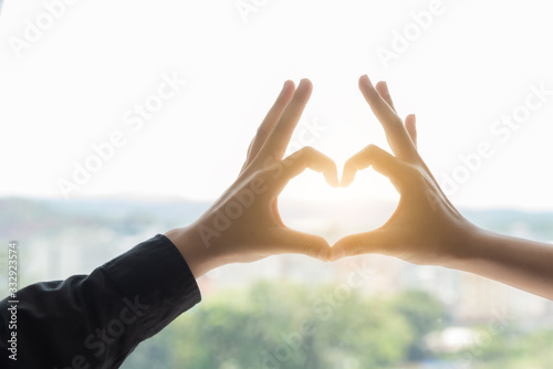 Two hand touch together in a heart shape on nature background. photo