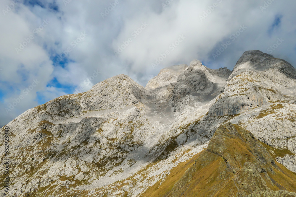 Golden colored mountains range at Austrian-Italian border. The autumn vibes in Alps, nature getting ready for hibernation. Sharp rocky Alpine peaks. Serenity and peace. Clouds breaching high mountains