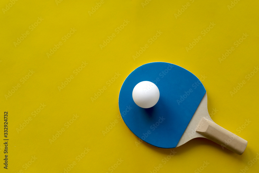 Table tennis rackets and white tennis ball lie on a bright multicolored background Table tennis rackets and white tennis ball lie on a bright multicolored background