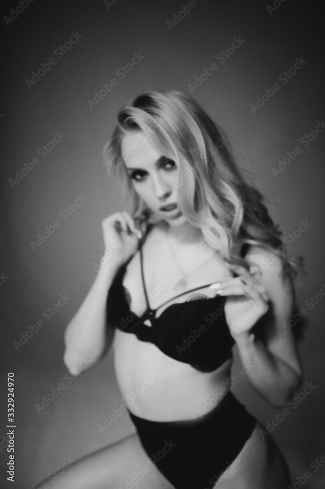 Fototapeta premium Blurred monochrome studio side portrait of young woman in black lingerie. Blur photo