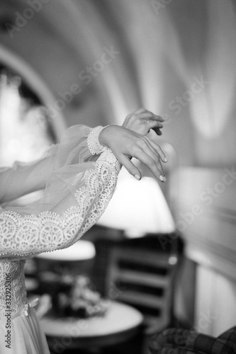  hands of the bride in a wedding dress with magnificent sleeves