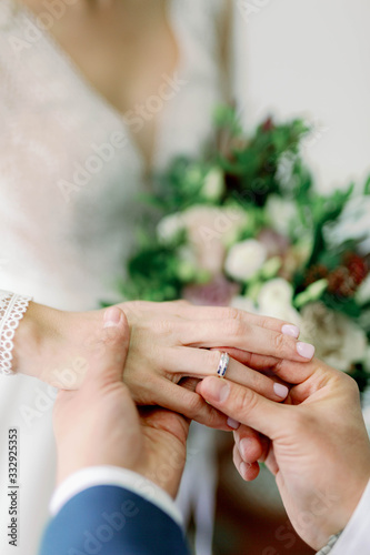 the groom puts a ring on the bride’s finger