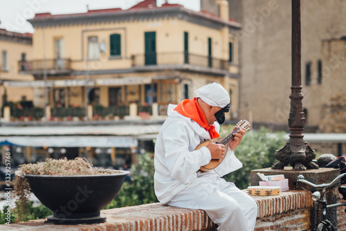 Billede på lærred The mask of Pulcinella (Punchinello) plays the mandolin on the Naples promenade