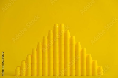 Yellow plastic building blocks in the shape of a pyramid on yellow background. Background of plastic details building blocks. Parts of bright small spare parts for toys. Copy  empty space for text