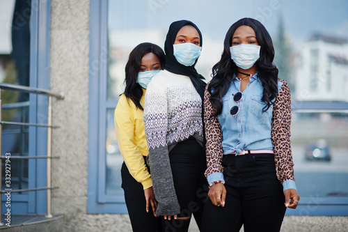 Group of three african american young volunteers wearing face mask outdoors. Coronavirus quarantine and global pandemic.