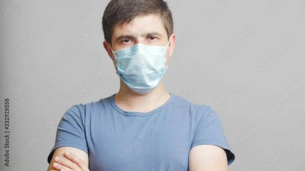confident young man in a protective mask on a gray studio background, quarantine measures, human ready to struggle
