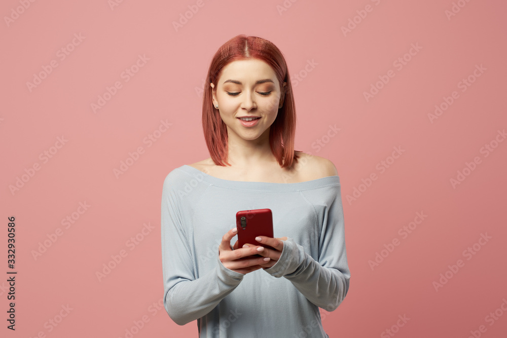 Smiling young woman with phone in her hands standing in studio Smiling young woman with phone in her hands standing in studio