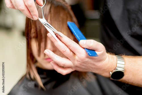 Hairdresser cuts hair of woman.