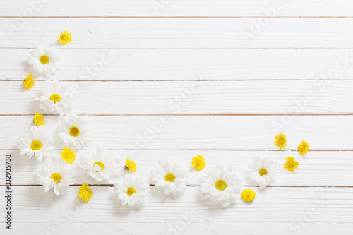 white chrysanthemum and yellow coltsfoot on white wooden background photo