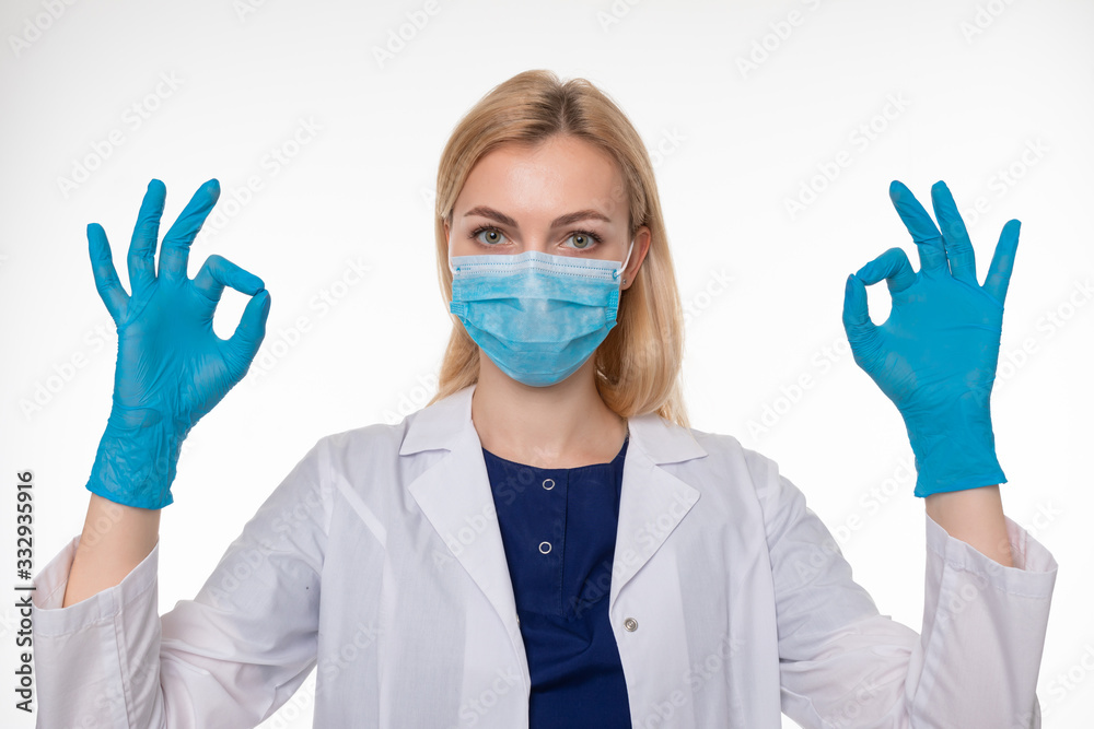 The doctor in a protective mask and gloves gestures ok