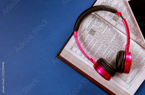 Open Holy bible book on headphones and mobile phone.