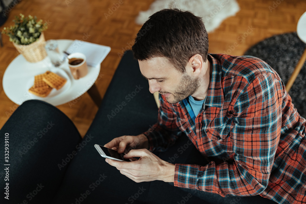 Young man typing text message on mobile phone at home. Young man typing text message on mobile phone at home.