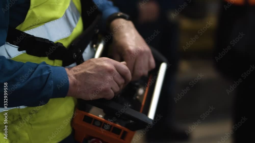 Close up of a worker inside a car manufacturing plant using a machinery handheld controller