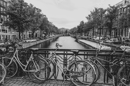 Schwarzweiß Aufnahme eines Kanals in Amsterdam mit Blick auf Fahrräder an einem Brückengeländer
