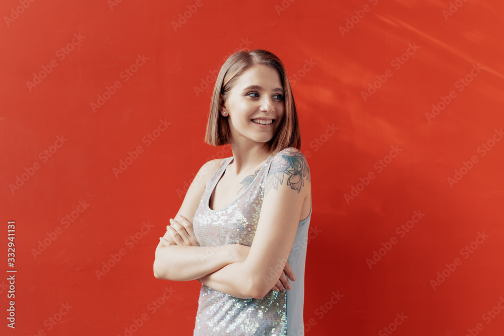 Fototapeta premium Cheerful young girl posing in front of a red wall
