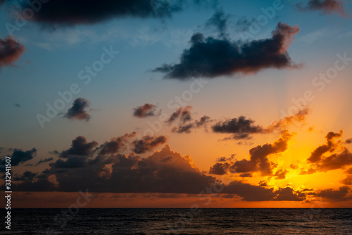 Shocking sunrise at the edge of the sea. Calm sunrise. The gold painted sky and dark clouds am...