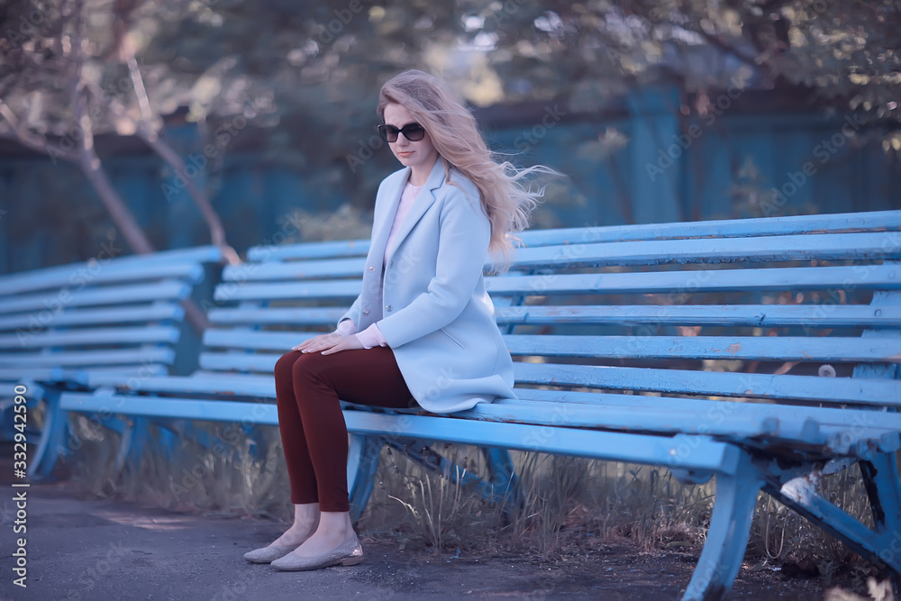 adult girl sitting on a bench in the park / beautiful model woman resting on a bench, cheerful happy girl adult girl sitting on a bench in the park / beautiful model woman resting on a bench, cheerful happy girl