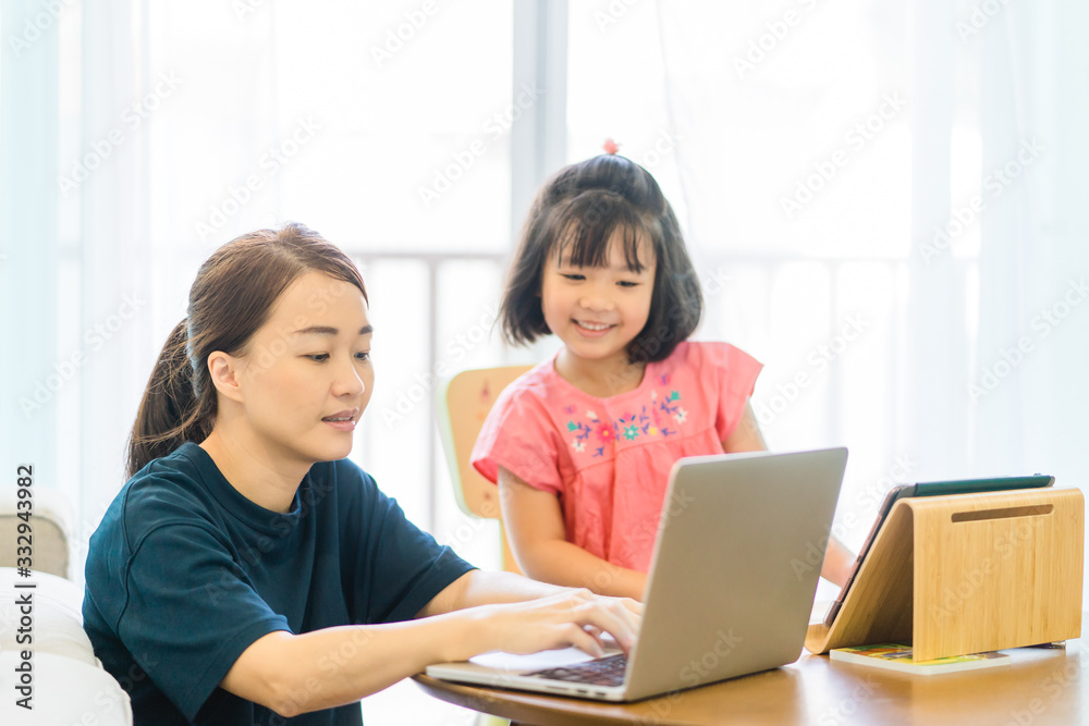Covid-19 Coronavirus and Learning from home, Home school kid concept.Little asian girl study with online learning and asian mother work from home with laptop.Quarantine and Social distancing concept. Covid-19 Coronavirus and Learning from home, Home school kid concept.Little asian girl study with online learning and asian mother work from home with laptop.Quarantine and Social distancing concept.