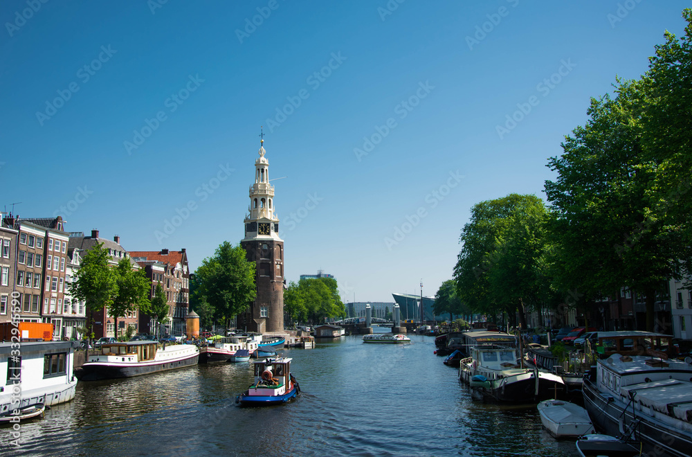 Summer cityscape of Amsterdam. Modern architecture. Touristic boats in canal. Tourism in Europe.
