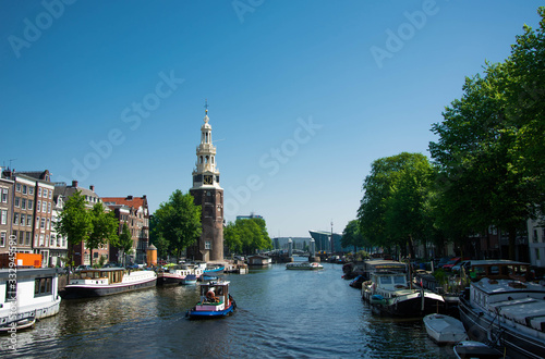 Summer cityscape of Amsterdam. Modern architecture. Touristic boats in canal. Tourism in Europe.