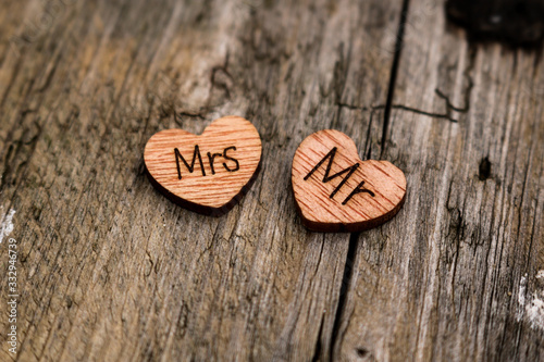 zwei Herzen aus Holz beschriftet mit Mr und Mrs auf einem alten Baumstamm