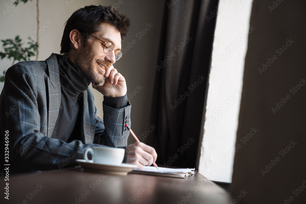 Image of smiling businessman examining documents and talking cellphone Image of smiling businessman examining documents and talking cellphone