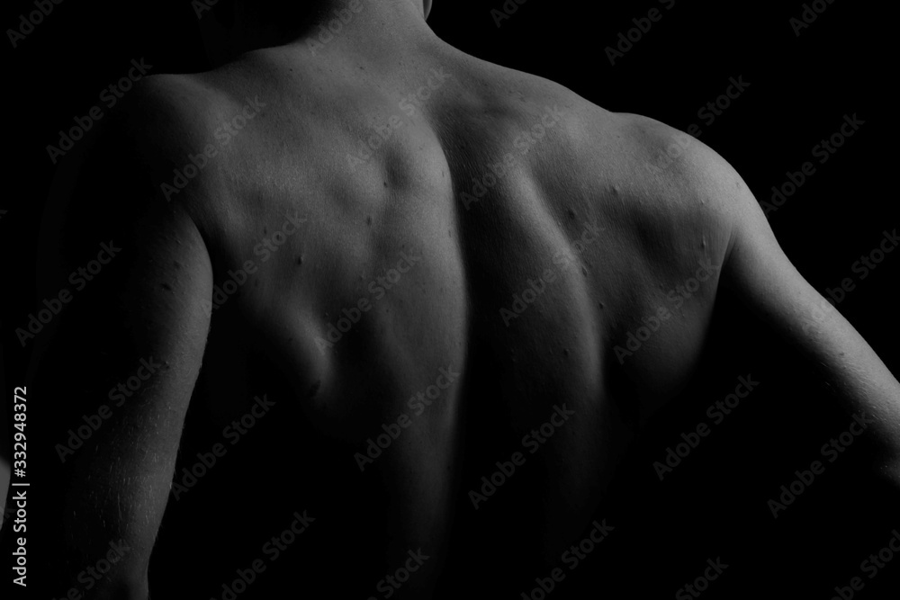 Back. The back of the man. Man holding a chain on his back in both hands. Chain. Black and white photo. Power. Sports Hall. Back. The back of the man. Man holding a chain on his back in both hands. Chain. Black and white photo. Power. Sports Hall.