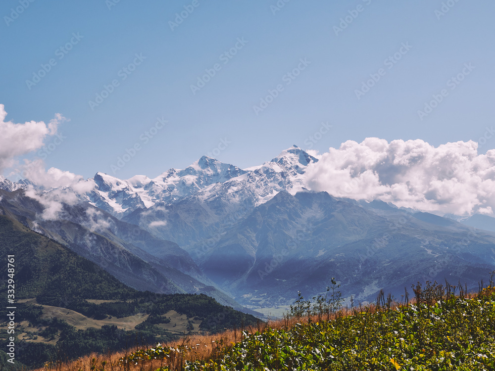 Fototapeta premium The majestic peak of Tetnuldi covered with snow on a sunny summer day in Caucasus mountains
