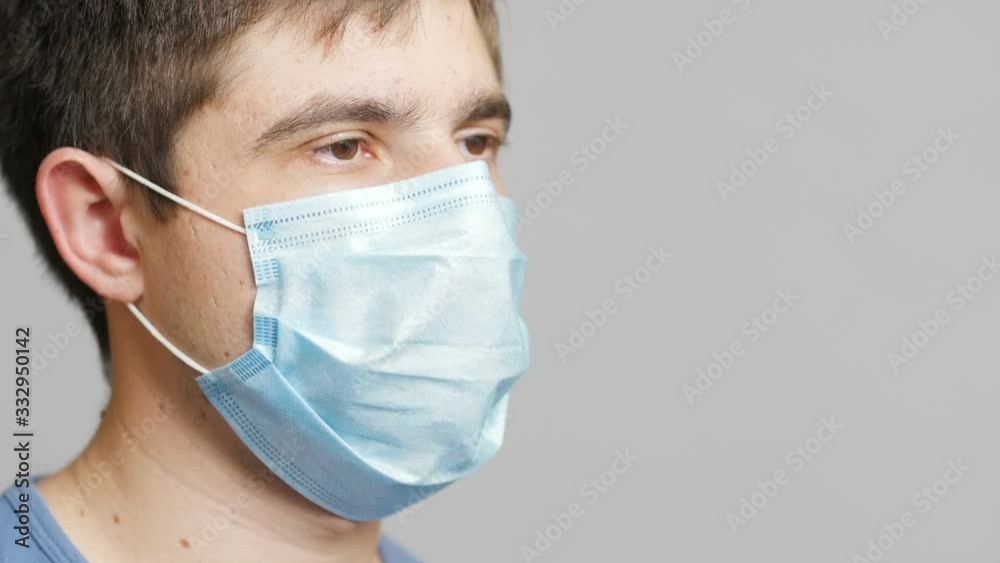 face of a young medical worker in a protective surgical mask looking tired at you and turning his head, concept medicine and health face of a young medical worker in a protective surgical mask looking tired at you and turning his head, concept medicine and health