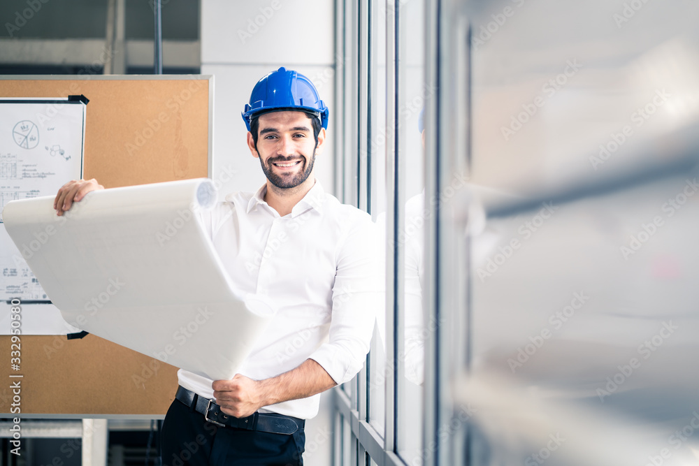 Caucasian young engineer home building member smile with new project planning while hold paper. The man hold blueprint of structure control in meeting room. Structure analysis home building concept. Caucasian young engineer home building member smile with new project planning while hold paper. The man hold blueprint of structure control in meeting room. Structure analysis home building concept.