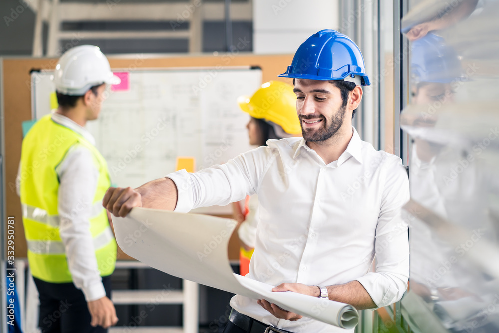 Caucasian man hold blueprint drawing while his team members looking project area. Young engineer group of home building member discuss for project planning.People brainstorm teamwork idea of structure Caucasian man hold blueprint drawing while his team members looking project area. Young engineer group of home building member discuss for project planning.People brainstorm teamwork idea of structure