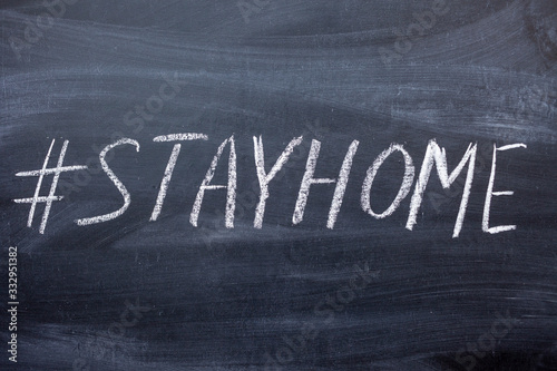 the hashtag stay at home is handwritten on a chalkboard.