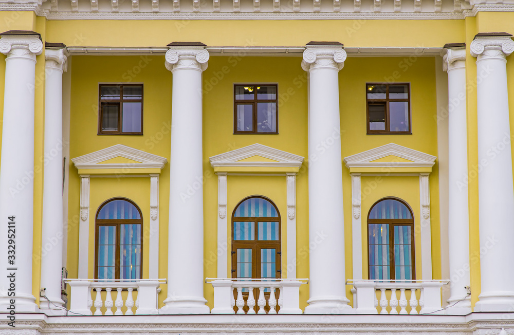 classic architecture building exterior facade symmetry background yellow walls and white marble columns arch shape of window