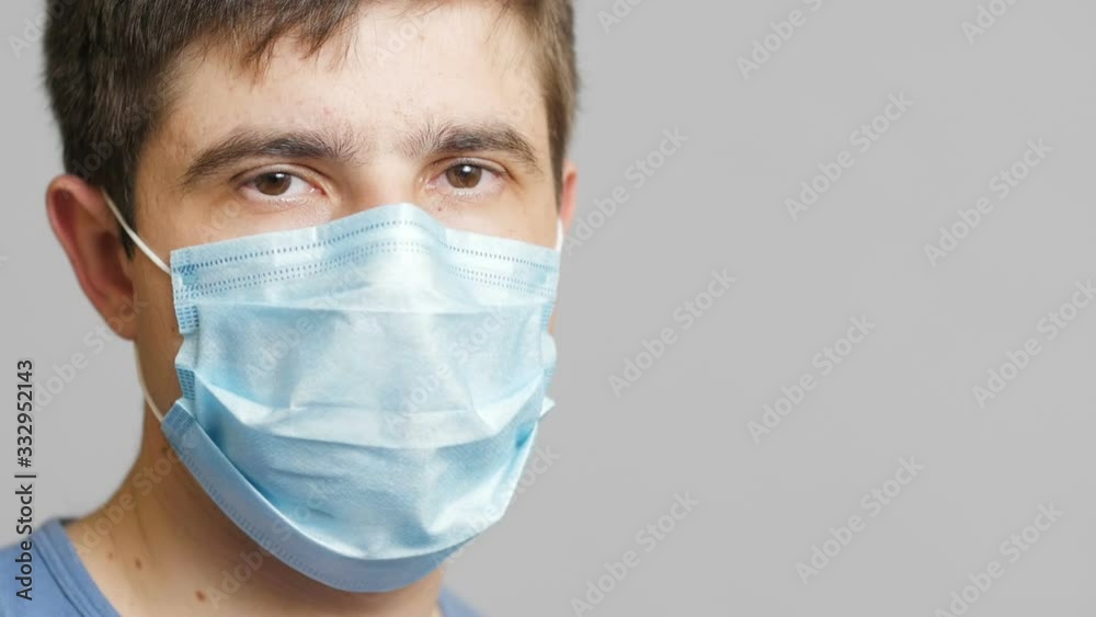 face of a young doctor in a protective mask looking tired at you and turning his head, concept medicine and health