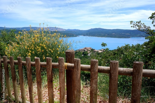 a brown fence with beautiful flower and amazing view of blue lake in South of France at Sainte Croix du Verdon, Valensole, Provence, France
