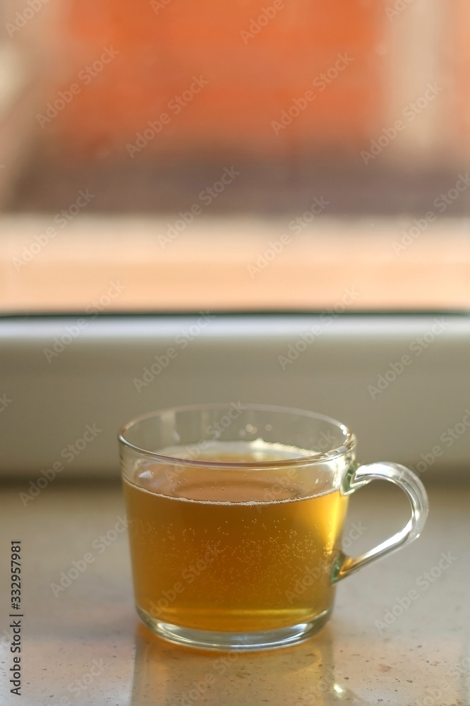 Cup of herbal tea on a window sill. Selective focus. Cup of herbal tea on a window sill. Selective focus.