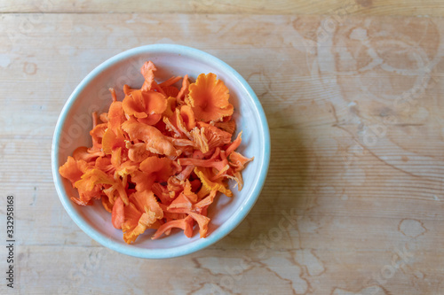 Bowl of bright red and orange cinnabar chanterelle mushrooms on a weathered wood background, copy space, horizontal aspect photo