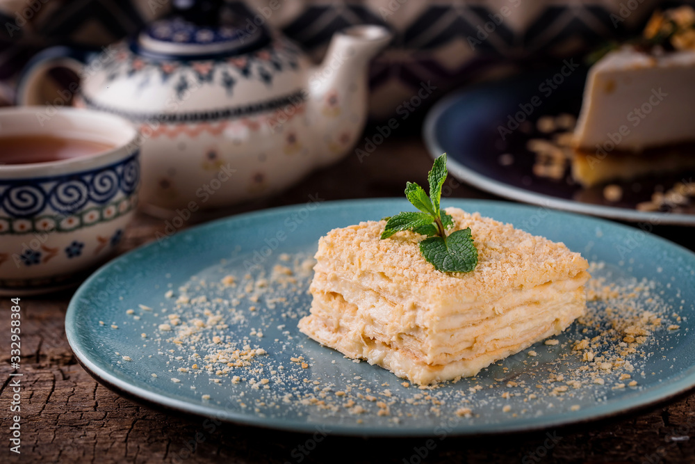 a piece of napoleon cake on a blue plate on a wooden table with mint a piece of napoleon cake on a blue plate on a wooden table with mint