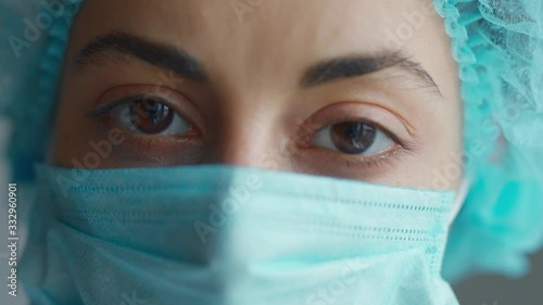 extreme closeup face and eyes woman doctor or nurse wearing medical cap and face mask looking at the camera. Ready to receive patients in hospital. Health care, medical concept.