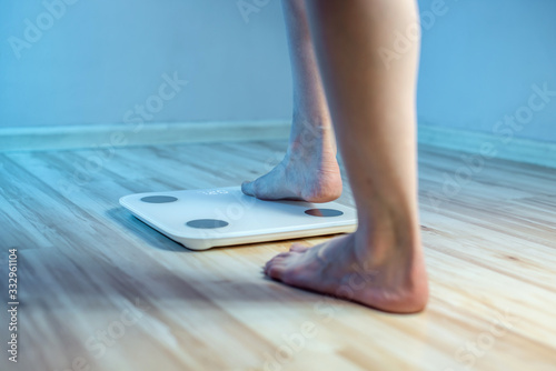 Women's bare feet stand on the floor electronic scales to check the weight and control the set of extra pounds