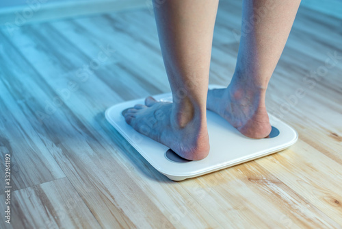 Women's bare feet stand on the floor electronic scales to check the weight and control the set of extra pounds