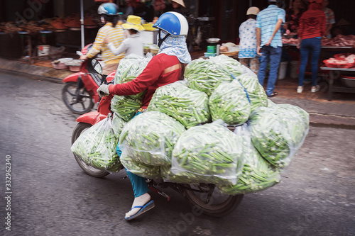 Person on scooter carrying green peas in street Can Tho