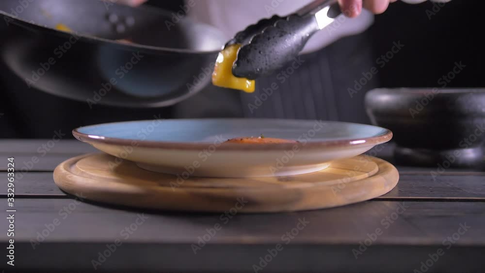 Close up of chef hand holding hot pan and adding salt to it with other hand Close up of chef hand holding hot pan and adding salt to it with other hand