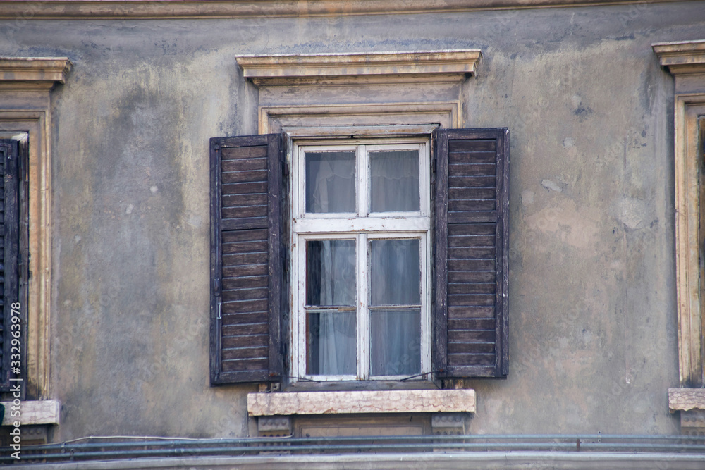 Italian window on the old wall facade with open wooden shabby brown paint shutters Italian window on the old wall facade with open wooden shabby brown paint shutters