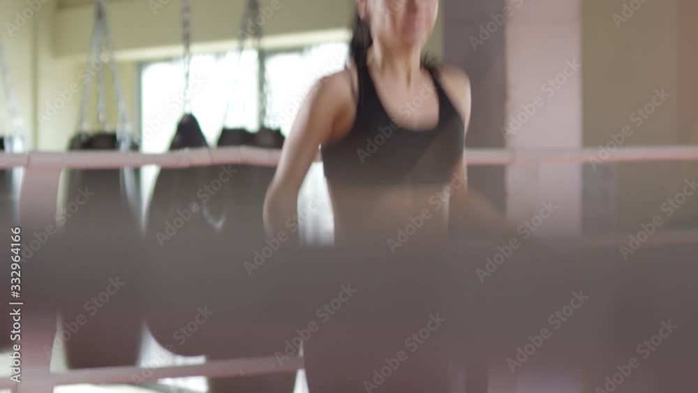 Professional female fighter in sportswear jumping the rope during workout in boxing ring Professional female fighter in sportswear jumping the rope during workout in boxing ring