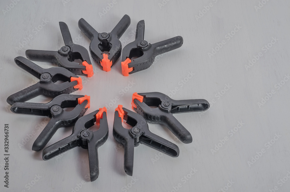 Black and orange construction clamps on a white background. Set of medium plastic clips. Clamping tools for carpentry. Hand tools for needlework. Black and orange construction clamps on a white background. Set of medium plastic clips. Clamping tools for carpentry. Hand tools for needlework.
