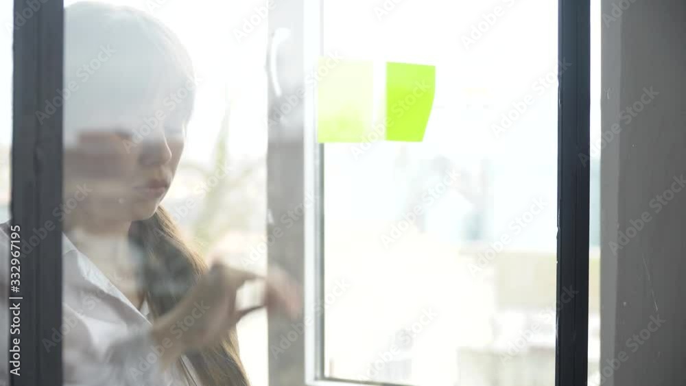 Secretary using sticky notes solving strategy on glass whiteboard Secretary using sticky notes solving strategy on glass whiteboard