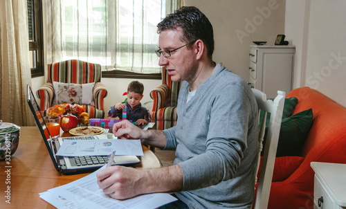 Father working at home while her son plays photo