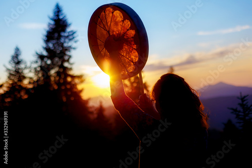 beautiful shamanic girl playing on shaman frame drum in the nature.